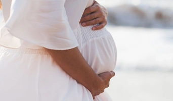 Mujer embarazada en la playa, símbolo de fertilidad tras FIV en Valencia.